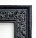 a black ornate frame with intricate floral designs on the edges.