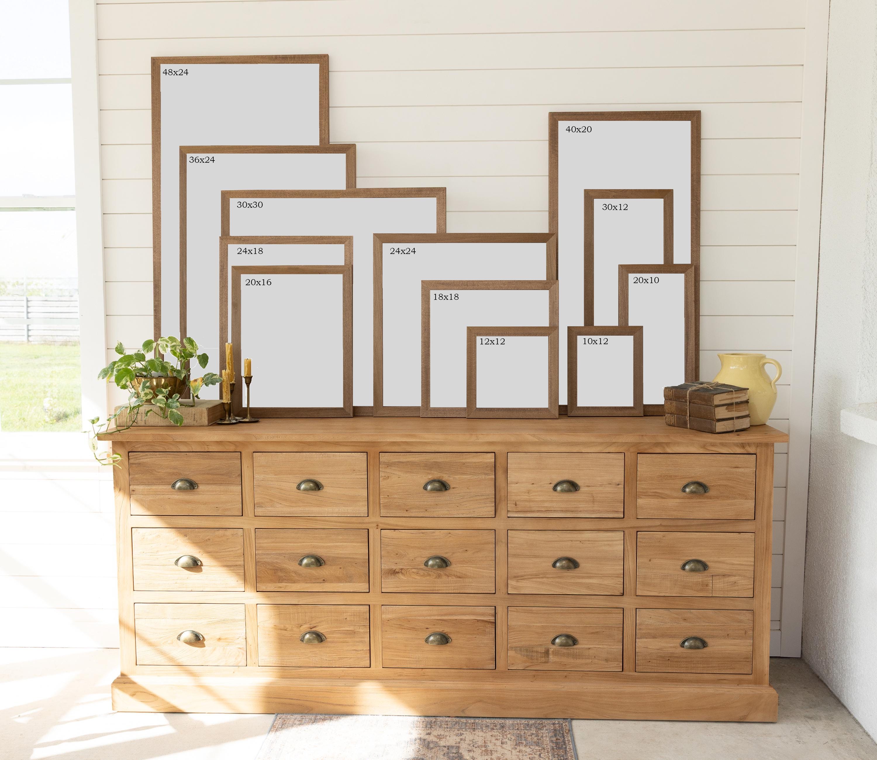 a wooden dresser with multiple drawers, each containing a different size of picture frame. The frames are arranged in a row, with varying sizes and shapes, creating a visually appealing display.