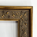 a close-up view of an ornate, gold-colored frame with intricate floral designs.