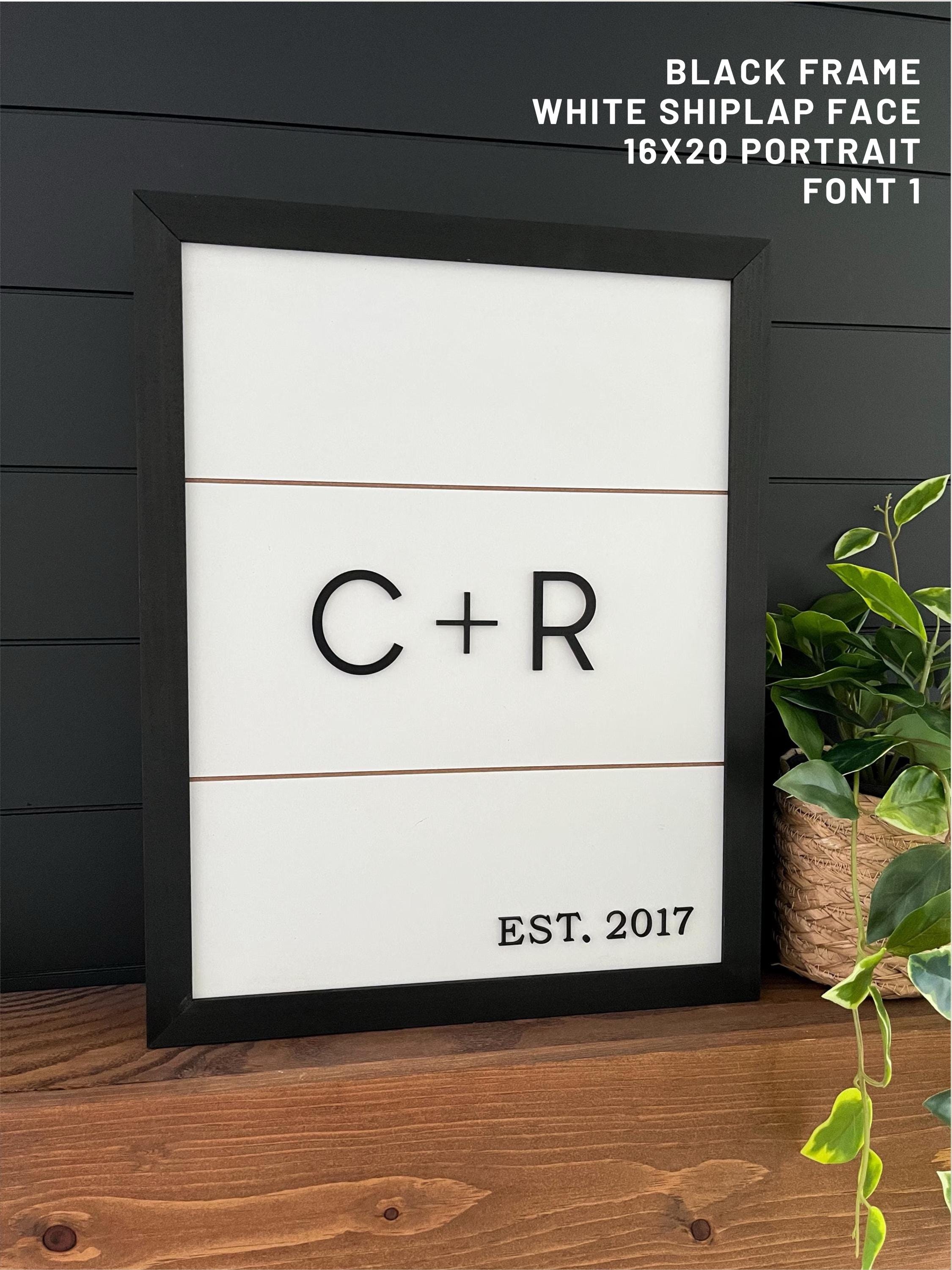 Framed concealment box with initials 'C + R' and 'EST. 2017' on a shiplap face, black frame.
